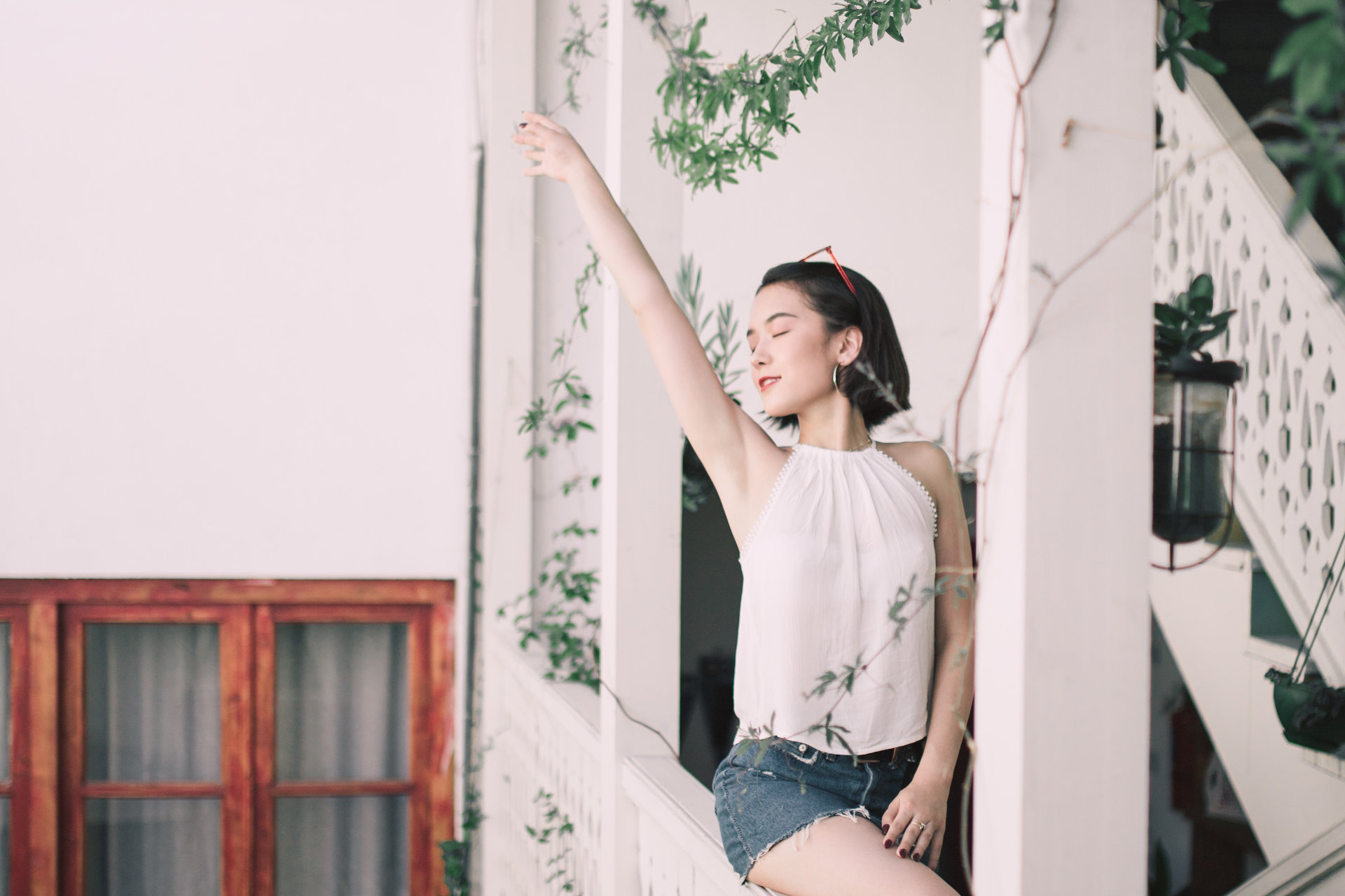 Happy woman is sitting on the stairs, raising her right hand.